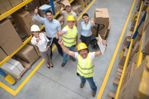 Photo of workers in warehouse giving the thumbs up signal