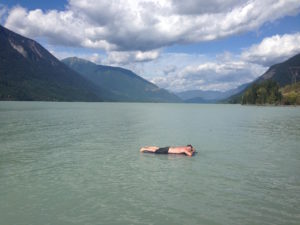 Photo of a person lying on an air mattress floating on a lake during summer