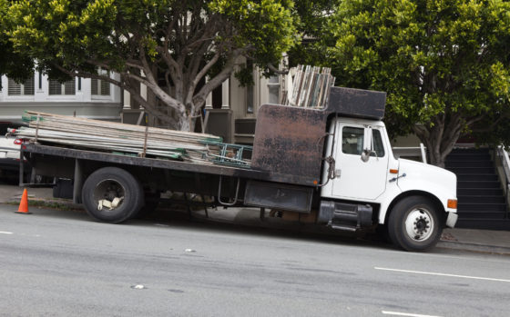 Photo of a flatbed truck delivering metal scaffolding, parked on a downhill slope