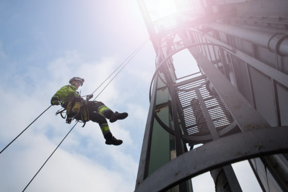 Photo of worker in safety gear abseiling down from a tower