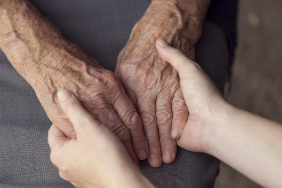 Photo of an older person's hands held caringly in a younger person's hands