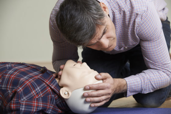 Photo of a man in a first aid class checking airway of CPR dummy