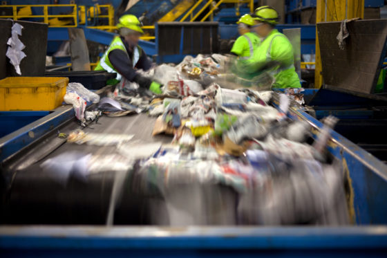 Photo of workers at a conveyor sorting materials for recycling