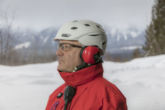 Photo of a ski guide wearing behind-the-head earmuffs, along with a helmet