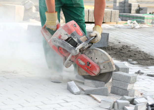 Photo of construction worker using saw to cut concrete