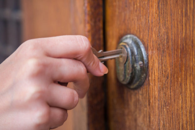 Photo of a hand holding a key, unlocking a door