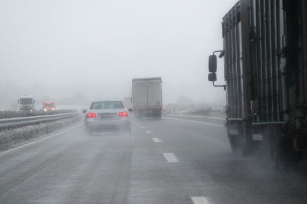 Photo of car and trucks driving on highway in winter