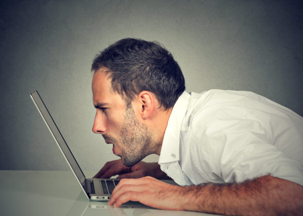 Photo of man with vision problems with his face almost touching laptop screen