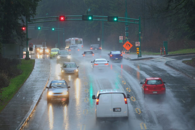 Photo of busy multi-lane roadway with signs and lights, and heavy rain