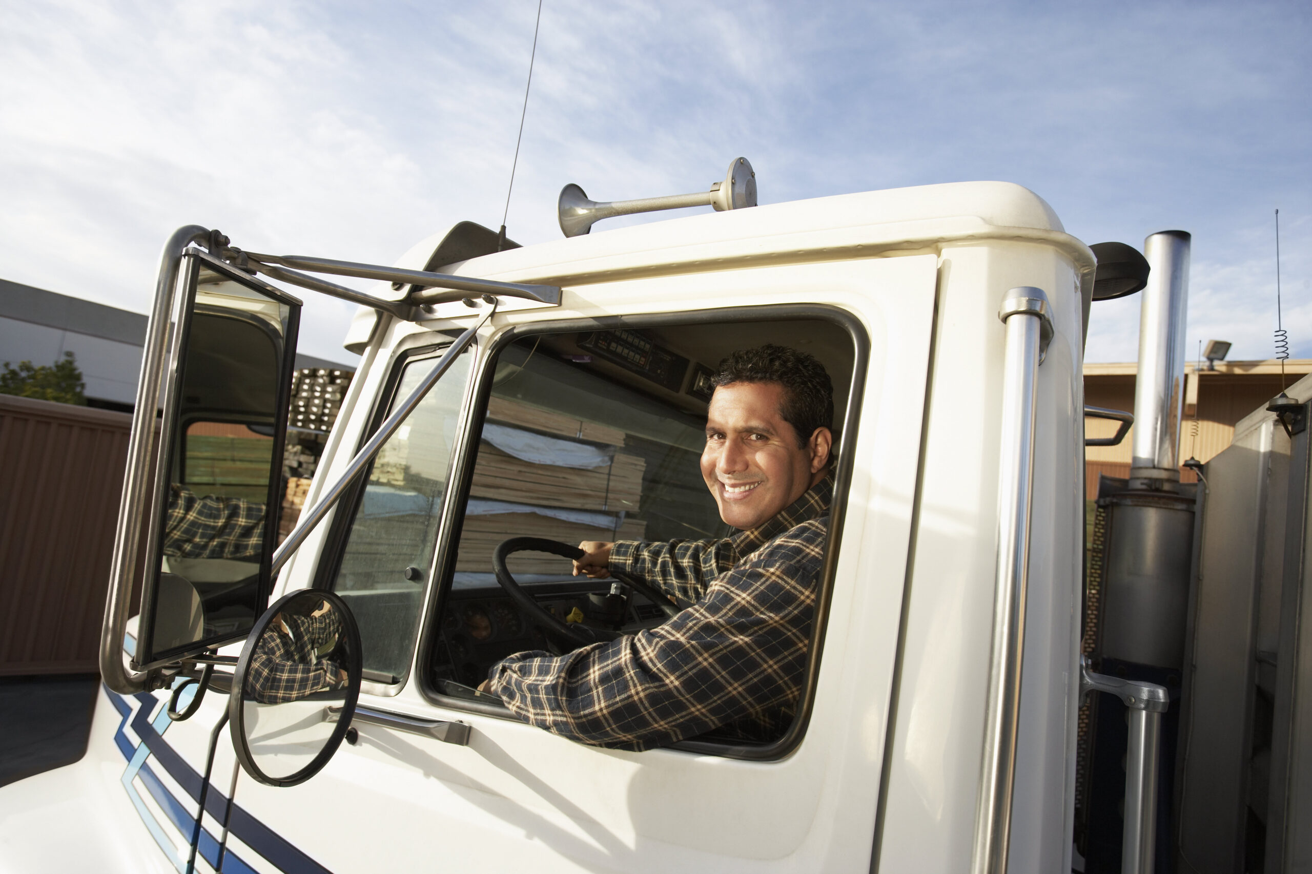 Photo of smiling truck driver in cab of semi truck