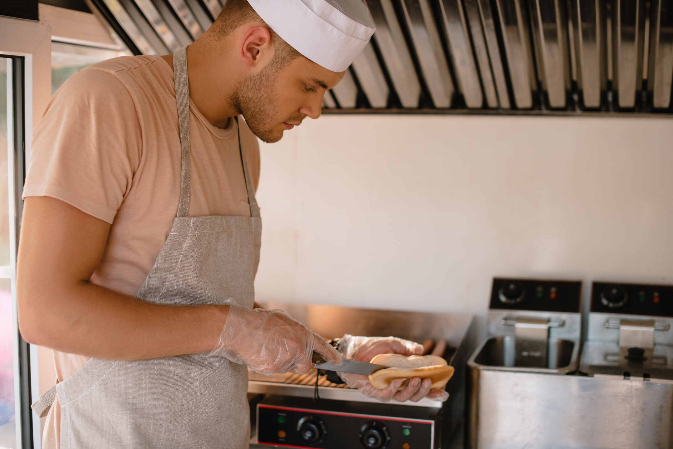 Photo of a cook in a food truck preparing a hotdog bun