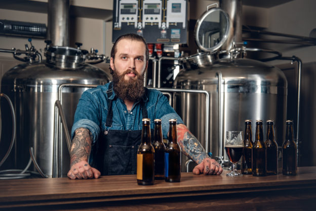 Photo of tatooed man behind counter in a craft brewery