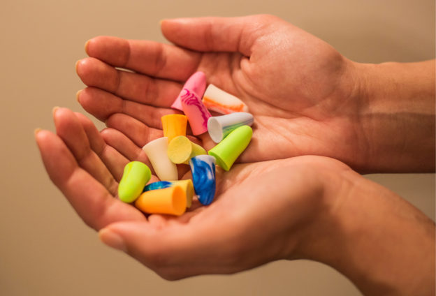 Different styles of earplugs in a person's hands