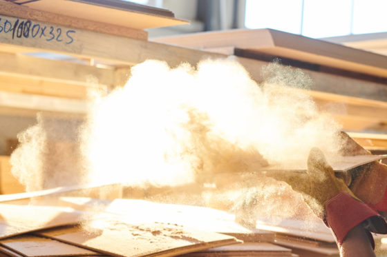 Photo of sawdust being blown off a board in a wood products plant