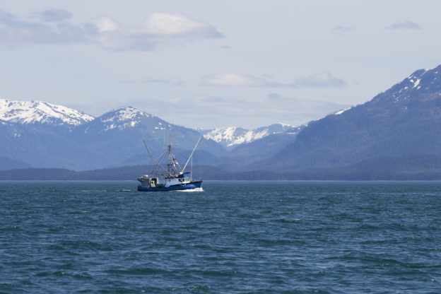 Photo of a fishing boat with snow-covered mountains in the background
