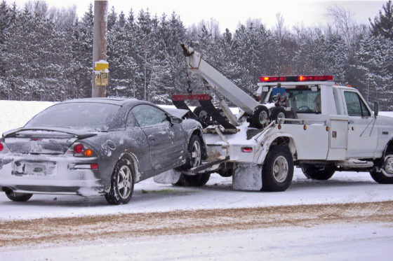 Photo of a towtruck with car winched up behind it, in snow