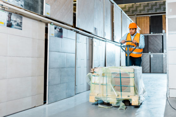 Photo of a worker using a powered pallet jack in a warehouse