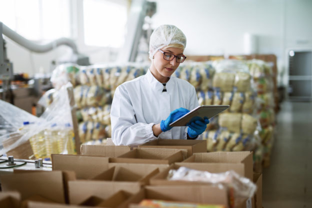 Photo of worker using tablet for checking boxes in food factory