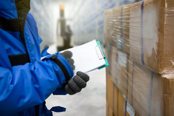 Photo of worker with clipboard in freezing room of a warehouse