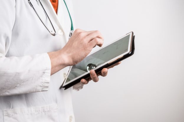 Photo of doctor in white coat using tablet