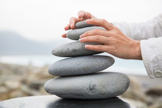 Photo of person's hands stacking stones into a balanced pyramid