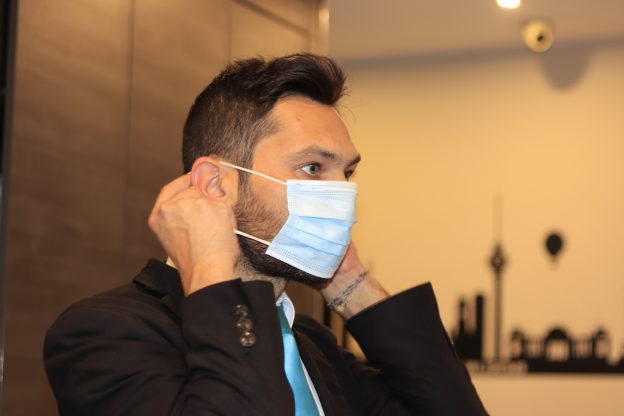 Photo of business man putting on reusable face mask