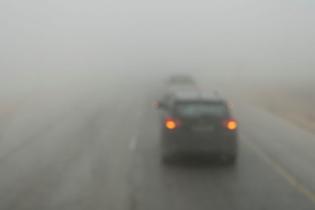 Photo of cars driving in dense smoke, with tail lights on