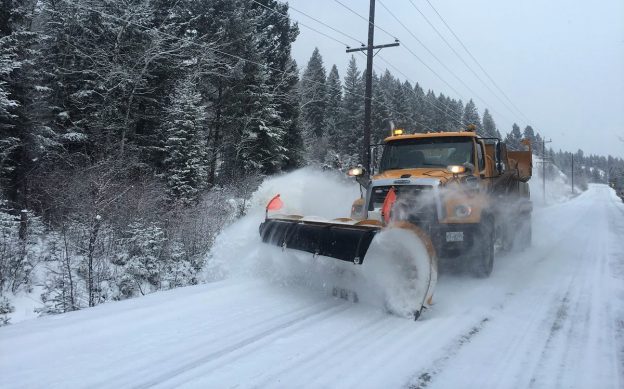 Photo of a snowplow plowing snow on the road in winter