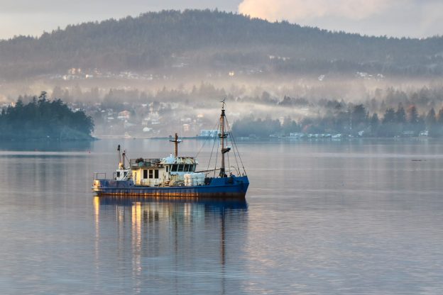Photo of Trawler vessel at anchor in a calm bay at Roche Cove, Sooke, British Columbia.