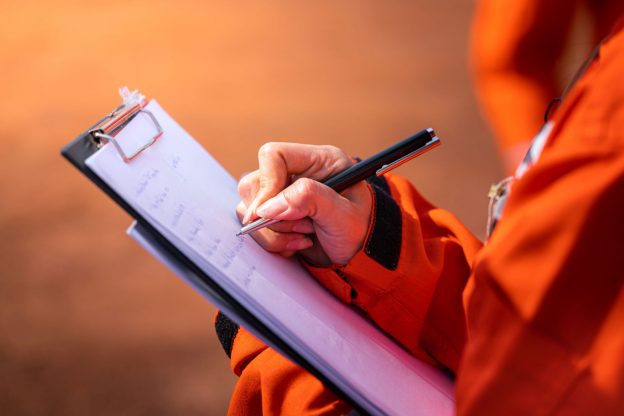 Photo of Prevention Officer hand writing note on a clipboard