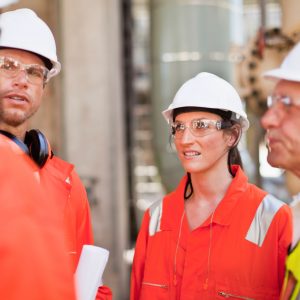 Photo of a group of workers wearing hard hats and safety glasses, standing for a safety meeting