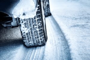 Photo of a rear winter tire of a car driving on a snow covered road