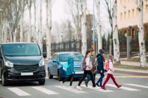 Photo of school children crossing the road while cars are stopped.