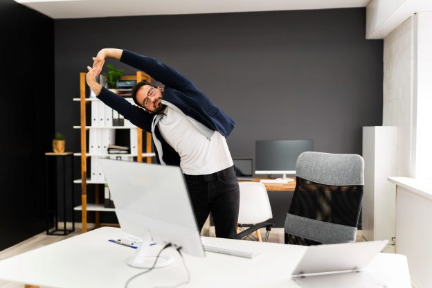 Photo of man working at a desk and stretching
