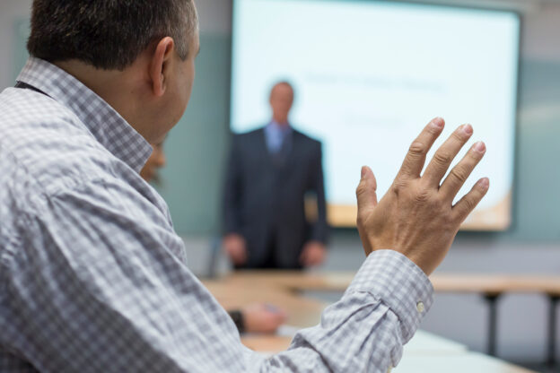 Photo of a male raising hand in a meeting.