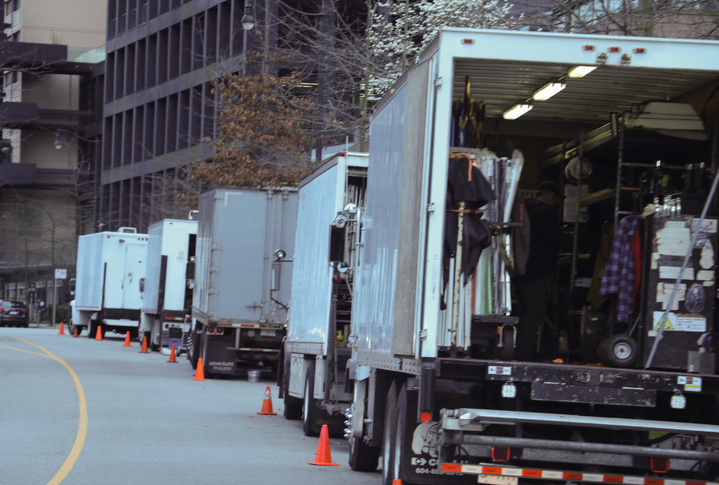 Movie or TV production truck line a city street.