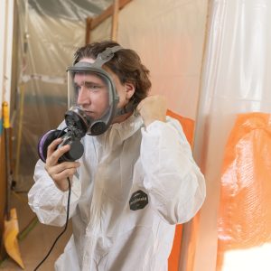Photo of a male putting on PPE on an asbestos abatement site.