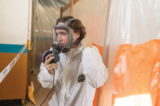 Photo of a male putting on PPE on an asbestos abatement site.
