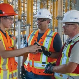 Photo of two men and a woman in PPE talking at a construction site.