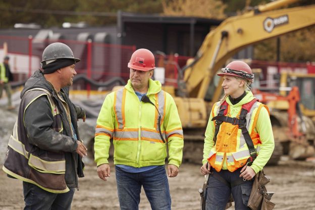 Photo of two males and one female talking at a construction site.