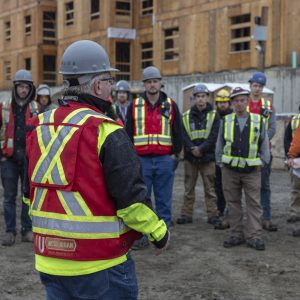 Construction lead speaking to group of construction workers on site.