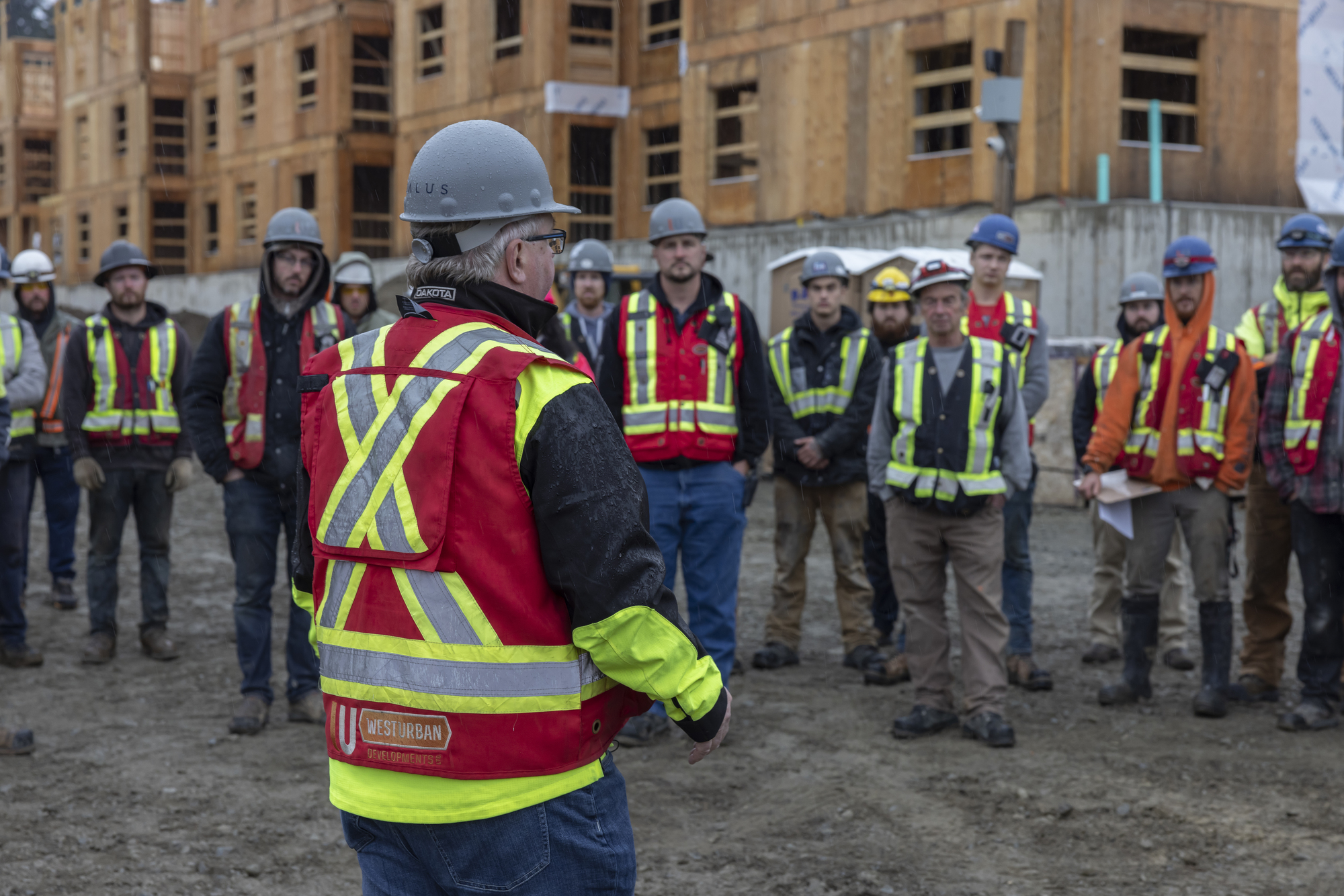 Construction lead speaking to group of construction workers on site.